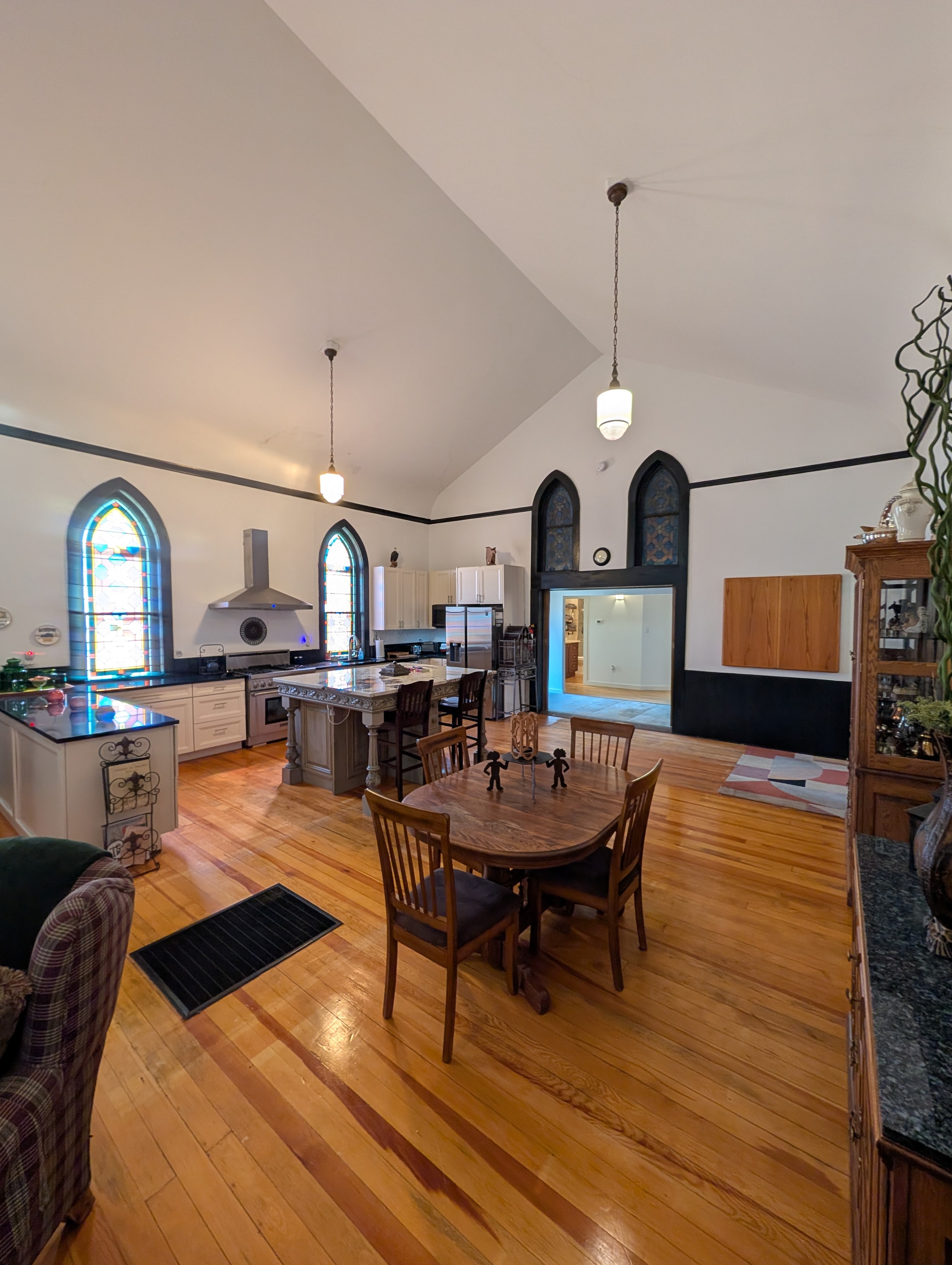 Grand chapel interior with vaulted ceiling, kitchen island, stained glass, and hardwood floors