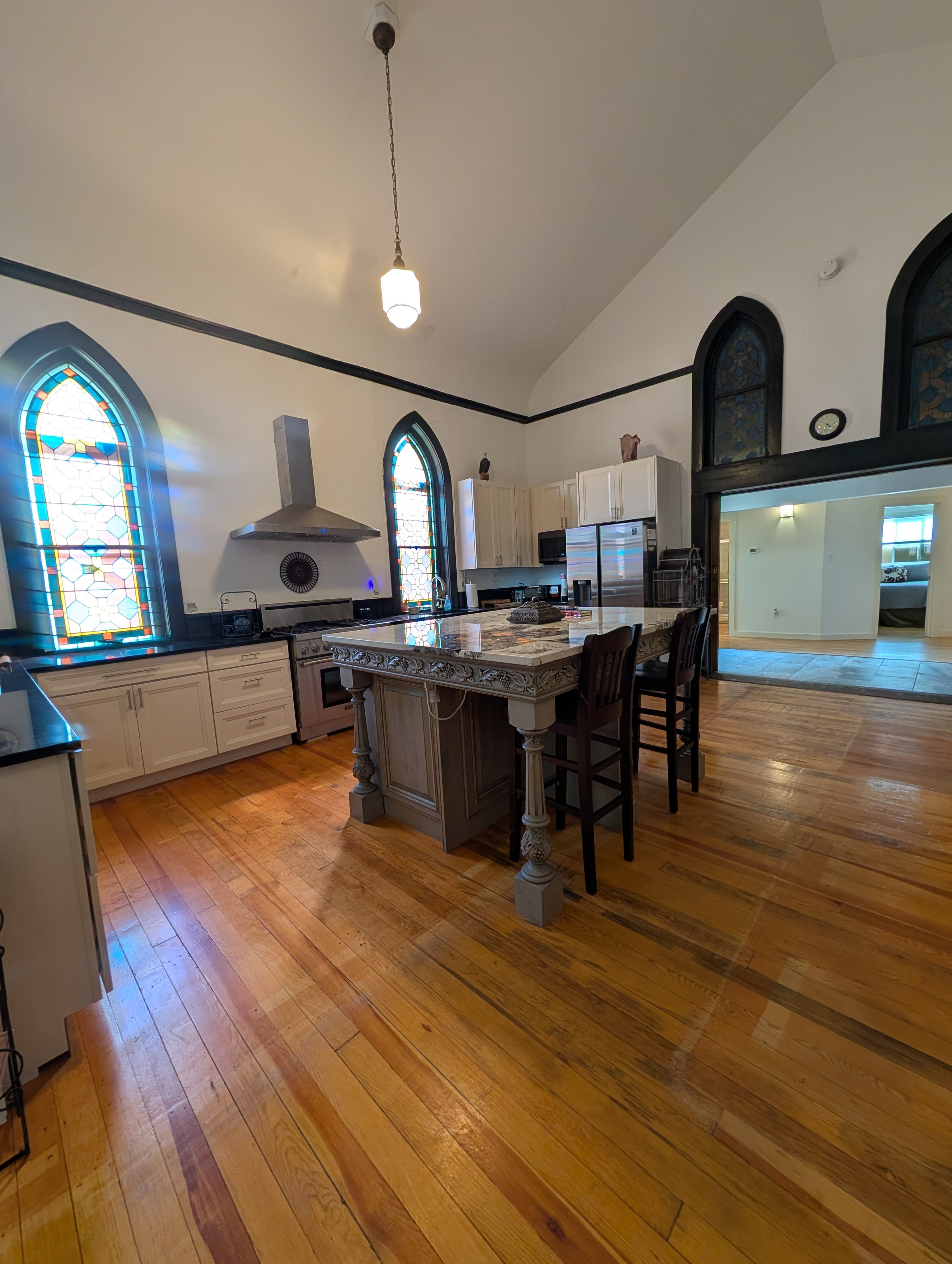 Open chapel gathering space with kitchen, dining area, and arched stained glass windows