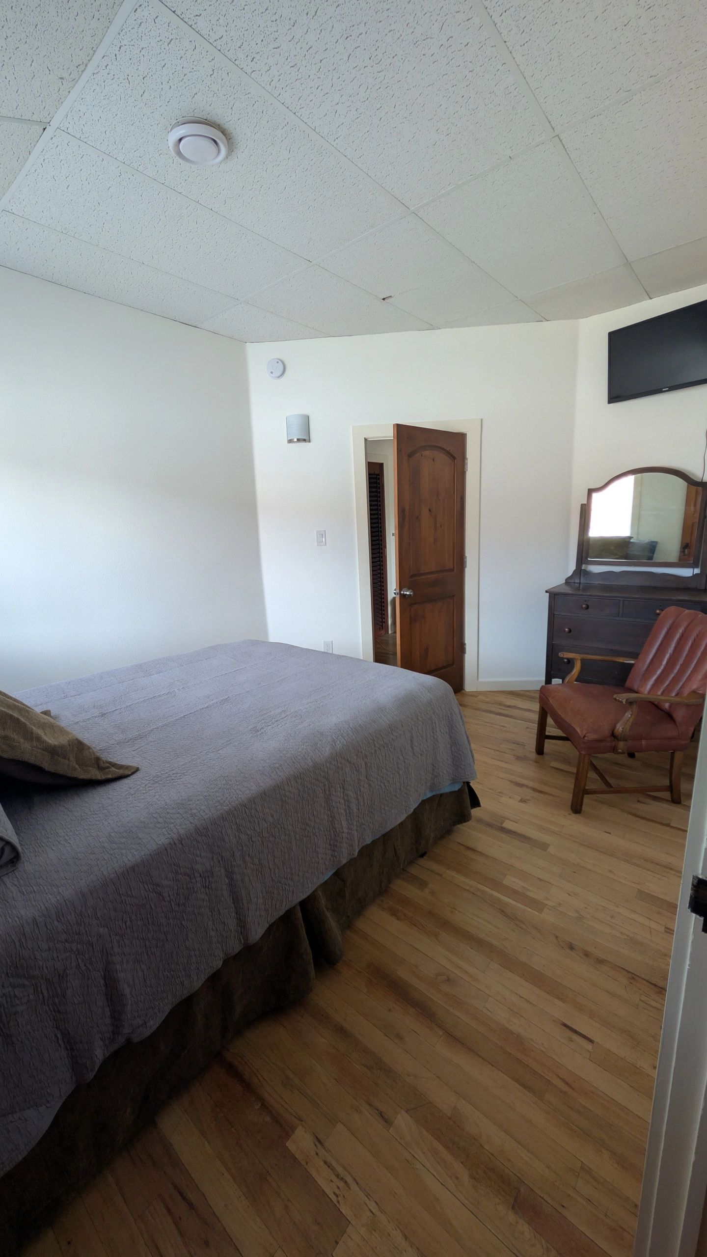 Bedroom with queen bed, tile floors, and arched stained glass window